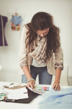 Gülümseyen kadın moda tasarımcısı ofis masasında oturuyor.