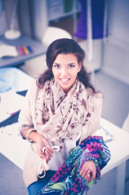 Gülümseyen kadın moda tasarımcısı ofis masasında oturuyor.