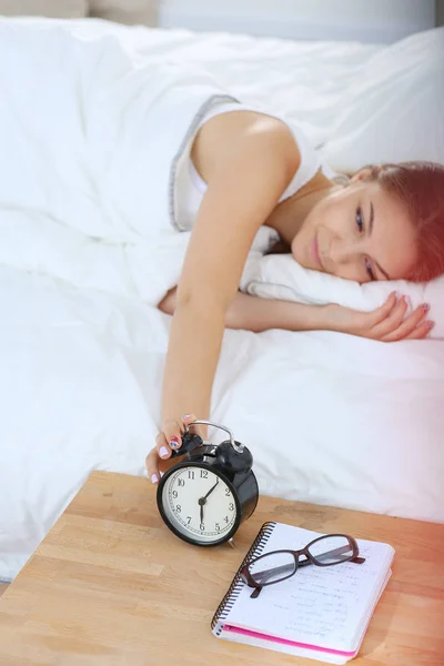 Una mujer joven apagando su despertador por la mañana. — Foto de Stock