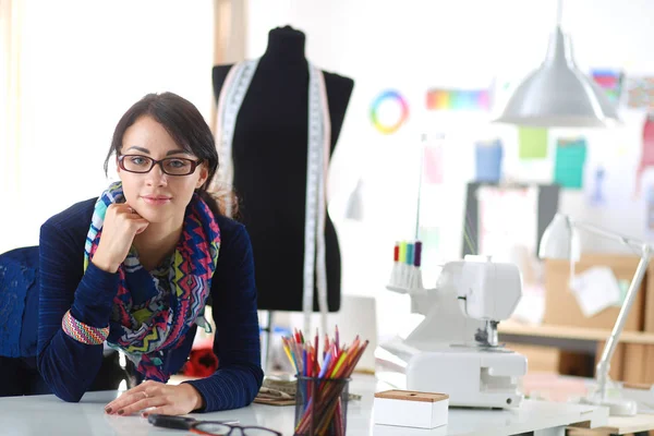 Beautiful fashion designer sitting at the desk in studio . — Stock Photo, Image