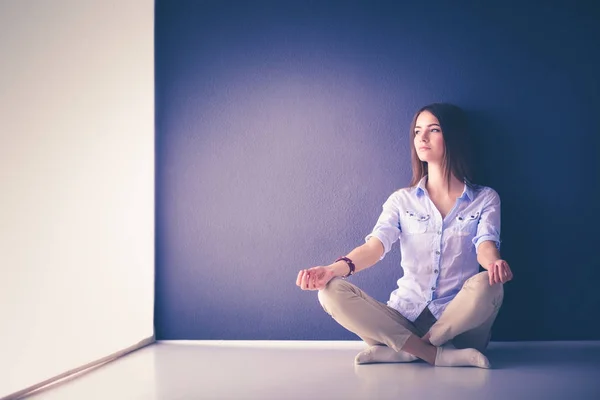 Jovem mulher sentada no chão perto da parede escura — Fotografia de Stock