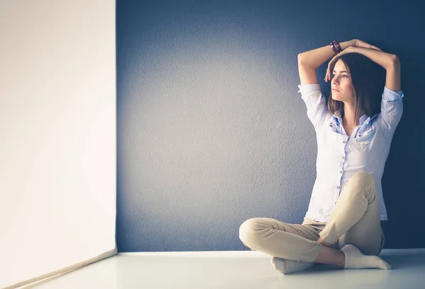 Young woman sitting on the floor near dark wall — Stock Photo, Image