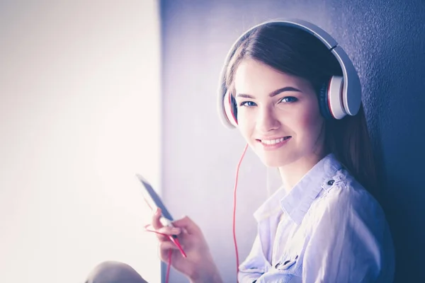 Mujer escuchando música en auriculares sobre fondo alféizar de ventana — Foto de Stock
