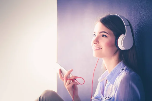 Woman listening music in headphones on windowsill background — Stock Photo, Image