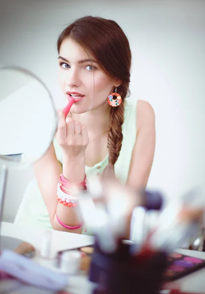 Genç güzel kadın ayna, Masa başında oturan yakınındaki makyaj yapma — Stok fotoğraf