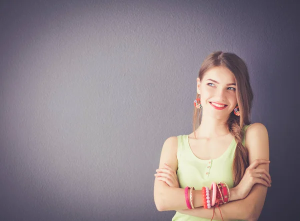 Aantrekkelijke jonge vrouw staande op een grijze achtergrond — Stockfoto