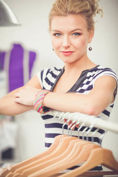 Mulher estilista jovem bonita perto de rack com cabides — Fotografia de Stock
