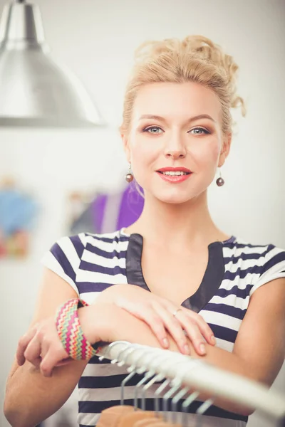 Beautiful young stylist woman near rack with hangers — Stock Photo, Image