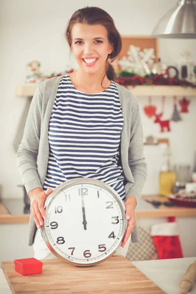 Happy young woman showing clock in christmas decorated kitchen — Stock Photo, Image