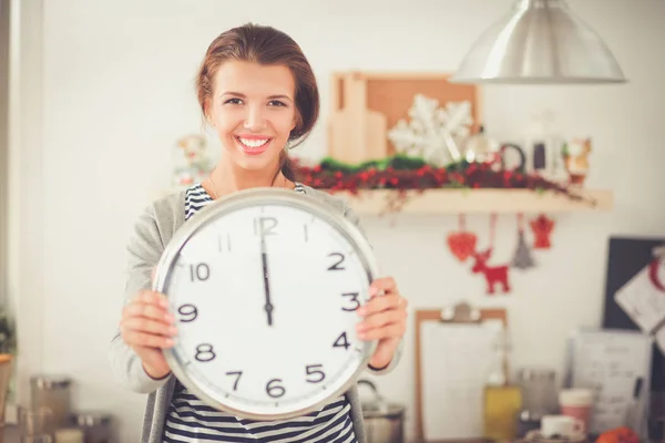 Feliz joven mujer mostrando reloj en la cocina decorada de Navidad —  Fotos de Stock