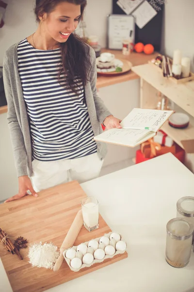 Gelukkig jong vrouw tonen klok in kerst versierd keuken — Stockfoto