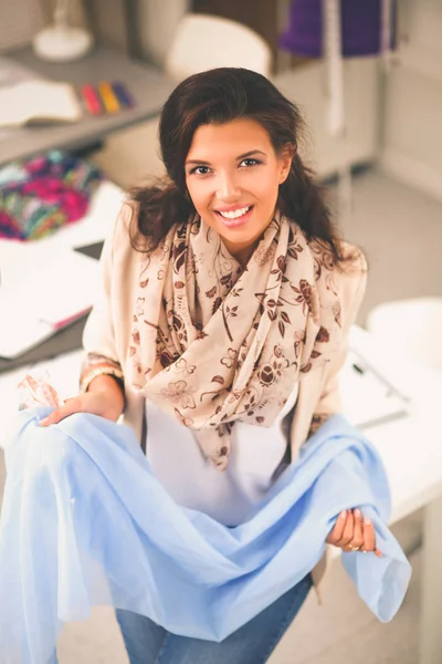 Glimlachende vrouwelijke mode-ontwerper zit aan het bureau — Stockfoto