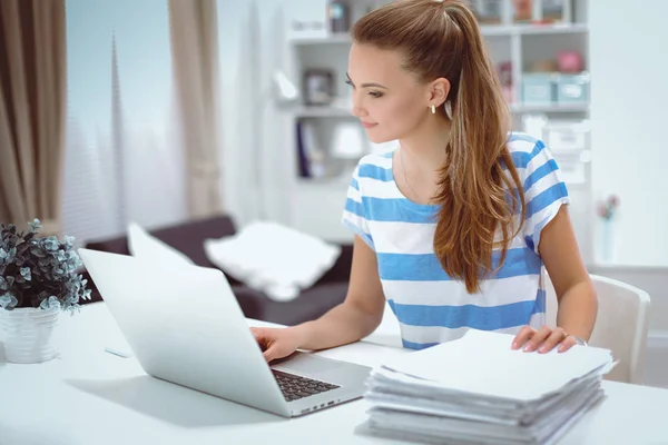 Mulher sorridente com documentos sentados na mesa com laptop. — Fotografia de Stock