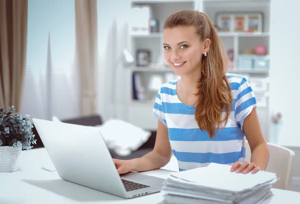 Lächelnde Frau mit Dokumenten auf dem Schreibtisch mit Laptop. — Stockfoto