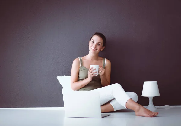 Портрет девушки, сидящей на полу и использующей ноутбук — стоковое фото