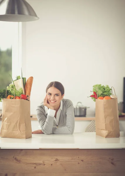 Sebzeli alışveriş torbası tutan genç bir kadın. Mutfakta duruyor. — Stok fotoğraf