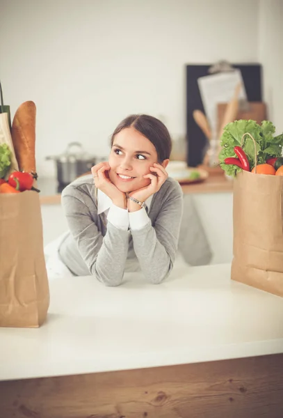 Young woman holding grocery shopping bag with vegetables . Standing in the kitchen — Stock Photo, Image