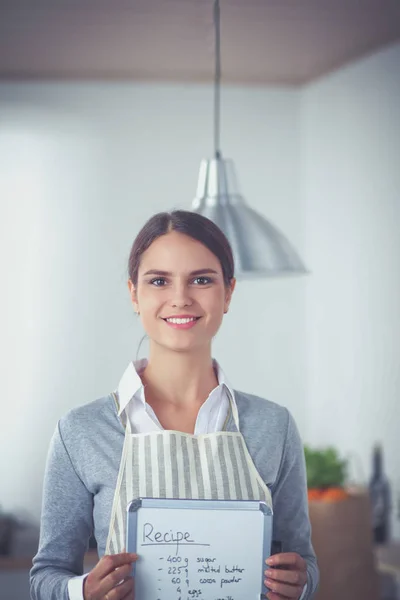 Donna in cucina a casa, in piedi vicino alla scrivania con cartella — Foto Stock