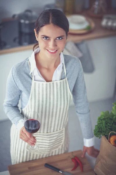 Mujer bonita bebiendo un poco de vino en casa en la cocina — Foto de Stock