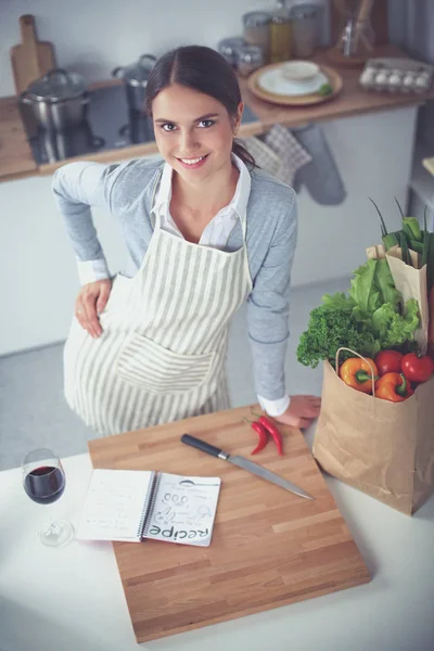 Mujer bonita bebiendo un poco de vino en casa en la cocina — Foto de Stock