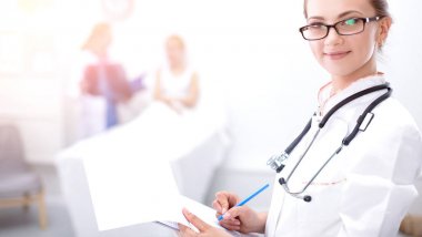 Genç bayan doktor hastanede steteskopla dikiliyor.