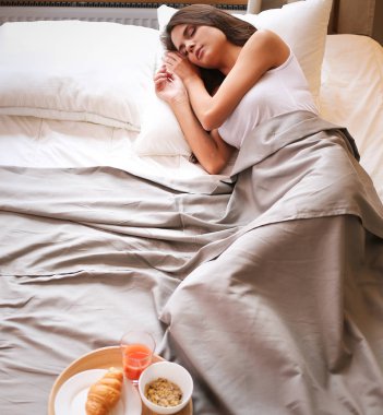 bir bardak süt ile yatakta oturan genç kadın