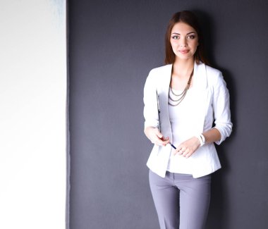 Bir dizüstü bilgisayar, gri arka plan üzerinde ayakta tutan genç kadın