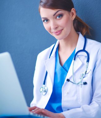 Gri arka planda oturan kadın doktor