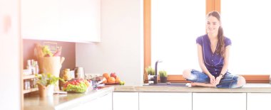 Lotus pozisyonunda mutfak masasında oturan genç güzel kadın