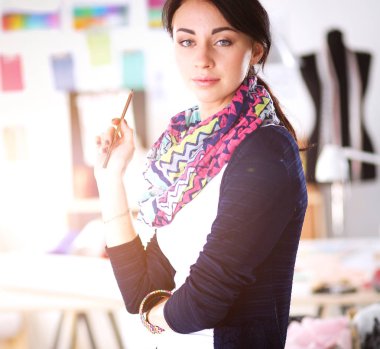 Güzel moda tasarımcısı stüdyoda duruyor. .