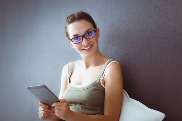 Atractiva chica caucásica sentada en el suelo con taza y tableta cerca de la pared — Foto de Stock