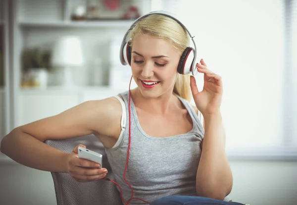 Jeune belle femme à la maison assise sur un canapé et écoutant de la musique — Photo