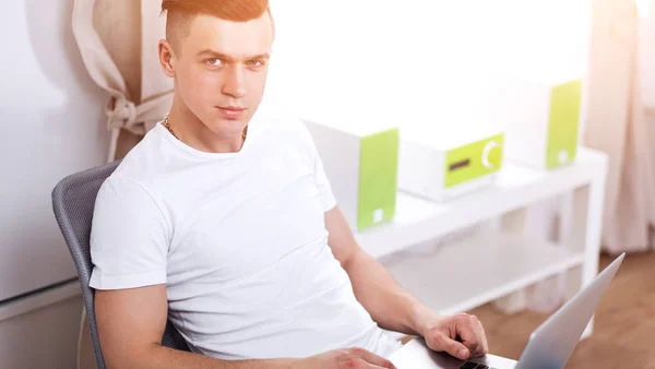 Young man sitting on chair with laptop — Stock Photo, Image