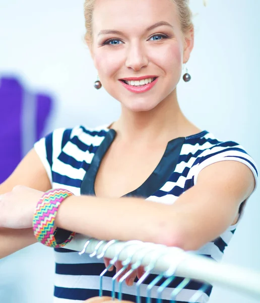 Piękny stylista młoda kobieta w pobliżu stojak z wieszakami — Zdjęcie stockowe