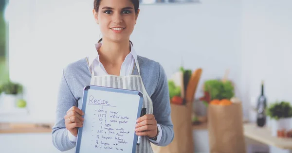 Kvinna i köket hemma, stående nära skrivbord med mapp — Stockfoto