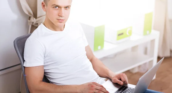 Young man sitting on chair with laptop — Stock Photo, Image