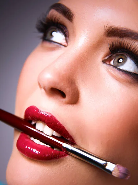 Womans lips holding make up brush — Stock Photo, Image