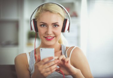 Evdeki genç ve güzel kadın kanepede oturup müzik dinliyor.