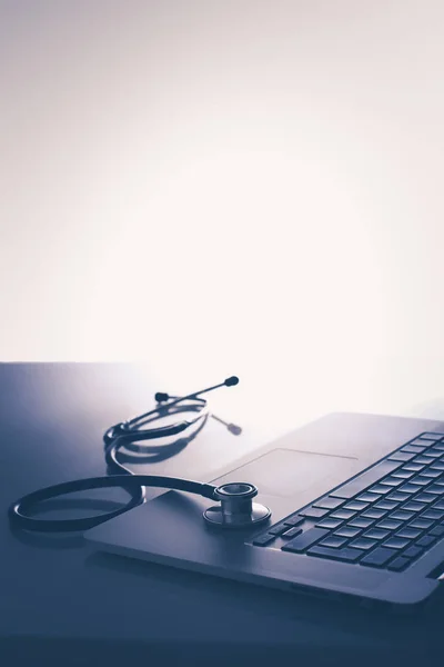 Lugar de trabajo del médico con portátil y estetoscopio y portátil en la mesa blanca — Foto de Stock