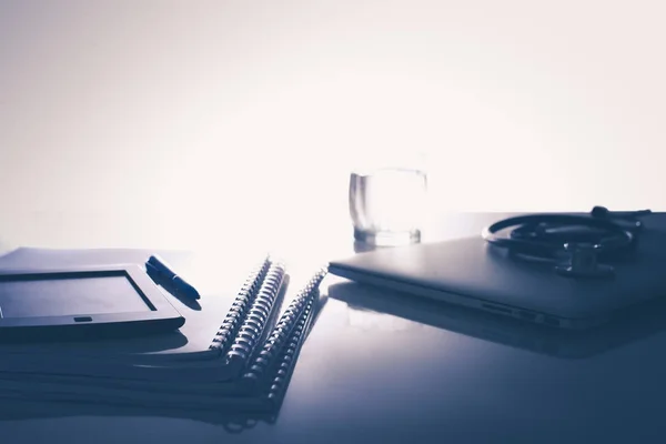 Lugar de trabajo del médico con portátil y estetoscopio y portátil en la mesa blanca —  Fotos de Stock