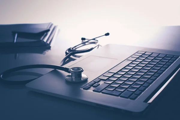 Workplace of doctor with laptop and stethoscope and notebook on white table