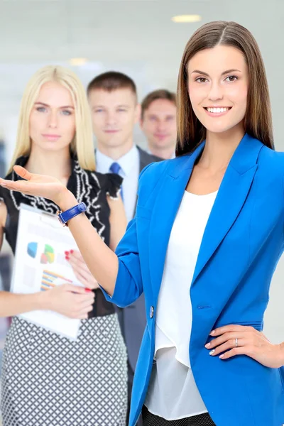 Business woman standing in foreground with a folder in her hands . — Stock Photo, Image