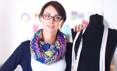 Gülümseyen moda tasarımcısı ofiste mankenin yanında duruyor.