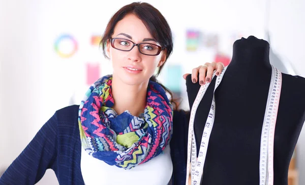 Gülümseyen moda tasarımcısı ofiste mankenin yanında duruyor.