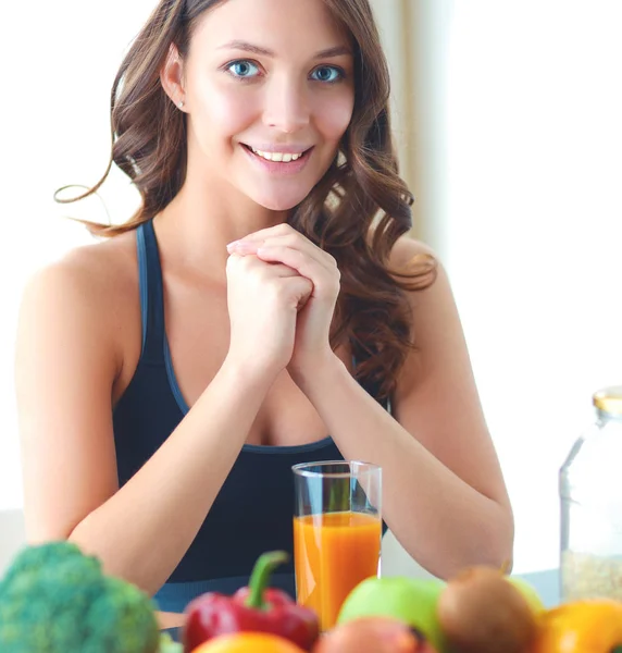 Menina sentada na cozinha na mesa com suco de frutas e copos — Fotografia de Stock