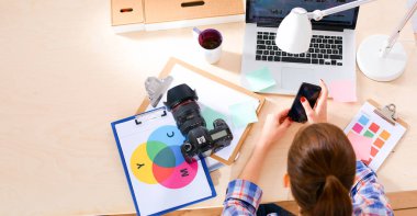 Masada dizüstü bilgisayarla oturan kadın fotoğrafçı.