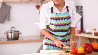 Gülümseyen kadın mutfakta salata hazırlıyor.