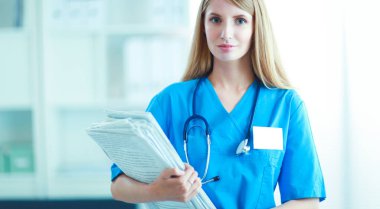 Hastane koridorunda klasörlü kadın doktor portresi.