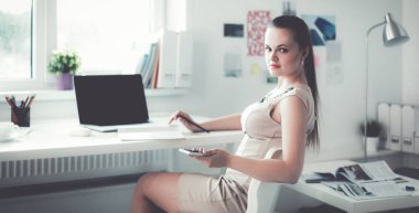 Elinde evrakları olan kadın masanın üstünde oturuyor.