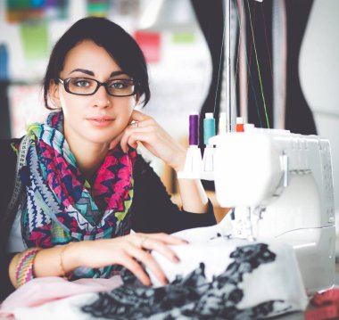 Çalışırken dikiş diken genç bir kadın.